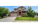Charming two-story home with a brick facade, well-maintained lawn, and attached garage at 19382 Dunraven St, Parker, CO 80134