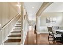 Hallway featuring hardwood floors, staircase with white railing, leading to the dining room and kitchen at 19382 Dunraven St, Parker, CO 80134