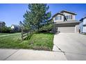 Two-story home featuring a two-car garage, mature tree, and a spacious front lawn at 11191 W Crestline Dr, Littleton, CO 80127