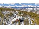 Snowy aerial view of a luxurious home nestled among the trees with mountain views at 1279 Estates Dr, Breckenridge, CO 80424