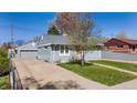 Gray home featuring a detached garage and a well-maintained front yard at 6981 Zuni St, Denver, CO 80221