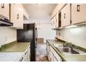 Functional kitchen features a black refrigerator, a stainless steel sink, and overhead cabinetry at 7755 E Quincy Ave # 104A6, Denver, CO 80237