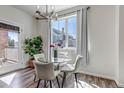 Bright dining area features a glass table, white chairs, modern lighting fixture, and a large window providing plenty of natural light at 1841 S Dunkirk St # 101, Aurora, CO 80017