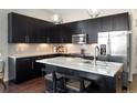 Modern kitchen features black cabinetry, stainless steel appliances, granite counters and pendant lighting at 336 E 1St Ave # 209, Denver, CO 80203