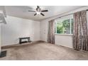 A cozy living room with neutral carpeting, a ceiling fan, and a large window dressed with patterned curtains at 1979 Beeler St, Aurora, CO 80010
