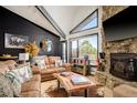 Cozy living room features a stone fireplace, leather sofas, wood floors, and large windows with scenic views at 610 Meadow View Dr, Evergreen, CO 80439