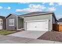 View of a single-Gathering home's garage with a concrete driveway and a well-maintained lawn at 869 Sawdust Dr, Brighton, CO 80601