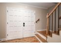 Welcoming entryway featuring wood floors, a staircase with wood banister and double doors at 8666 E Easter Ave, Centennial, CO 80112