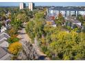 Aerial view of a quiet neighborhood featuring mature trees, walking paths, and modern buildings in the background at 1355 S Ulster St, Denver, CO 80231