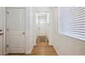 Bright hallway with wood floors leading to the front door and featuring white walls at 1107 Sunrise Dr, Brighton, CO 80603