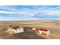 Expansive aerial view of a charming home with multiple outbuildings amidst a vast, open landscape at 4820 S County Road 137, Bennett, CO 80102