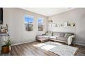 Bright living room boasts wood floors, a comfortable gray sectional, and sunlit windows with outside views at 16251 E 47Th Pl, Denver, CO 80239