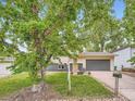 Charming home with mature trees, a well-kept lawn, and gray garage door at 12991 E Idaho Dr, Aurora, CO 80012