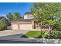 View of the home's front facade, showing the three car garage and a tree at 13018 Niagara Way, Thornton, CO 80602