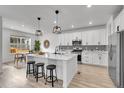 Modern kitchen features an island with seating, stainless steel appliances, and stylish black and white backsplash at 17809 Fox St, Broomfield, CO 80023