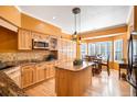 Spacious kitchen with wooden cabinets, granite counters, kitchen island, modern appliances, and adjacent dining area at 9875 Greensview Cir, Lone Tree, CO 80124