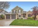 Charming two-story home featuring a well-manicured lawn and a three-car garage, set against a clear blue sky at 527 Stonemont Dr, Castle Pines, CO 80108