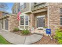 Inviting entrance with well-kept landscaping, a brick facade, a three-car garage, and patriotic decor at 527 Stonemont Dr, Castle Pines, CO 80108