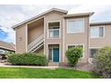 A shot of the exterior of the condo building showing the entry way, second story deck and well-manicured lawn at 3845 Canyon Ranch Rd # 102, Highlands Ranch, CO 80126