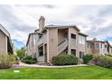 Exterior shot of the condo with a green lawn, walkway, and mature bushes that adds to its curb appeal at 3845 Canyon Ranch Rd # 102, Highlands Ranch, CO 80126