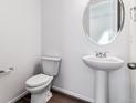 Clean, minimalist powder room featuring a pedestal sink, round mirror, and modern fixtures at 9165 Truckee Ct, Commerce City, CO 80022