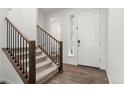 Bright foyer with wood-look floors, stairs with wood and iron railing, and a white front door at 656 N Bersshine St, Watkins, CO 80137