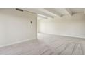 Empty living room featuring neutral walls, carpet, and modern ceiling beams at 130 N Pearl St # 1103, Denver, CO 80203