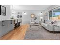 Open-concept living room with modern decor and hardwood flooring, complemented by a stylish kitchen and bar area at 3222 S Fairfax St, Denver, CO 80222