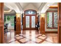 Elegant foyer featuring hardwood floors with decorative inlays, wood trim, and stained glass double doors at 4 Redhawk Run, Englewood, CO 80113
