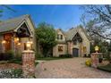 Charming stone home featuring a circular driveway with mature landscaping and unique architectural details at 4 Redhawk Run, Englewood, CO 80113