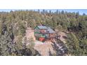 Hillside exterior view of home nestled in the trees with wraparound deck and garage at 1406 Pika Rd, Boulder, CO 80302