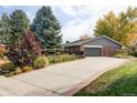 Home exterior with a wide driveway, a two-car garage, mature trees, and manicured landscaping at 1800 S Niagara Way, Denver, CO 80224