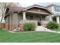 Inviting brick home featuring a tiled roof, a covered porch, and lush landscaping at 1395 S Josephine St, Denver, CO 80210