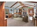 Cozy living room with wood paneling, stone fireplace, ceiling fan and exposed beams at 4960 S Fox St, Englewood, CO 80110