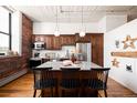 Modern kitchen features island with seating, wood cabinets, stainless steel appliances, and exposed brick at 2261 Blake St # 2G, Denver, CO 80205