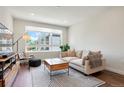 Sunlit living room showcasing large windows, a comfortable sofa, and a contemporary rug on dark hardwood floors at 2120 N Downing St # 209, Denver, CO 80205