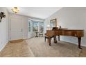 Cozy carpeted living room with a vintage piano and bay windows at 9662 Newcastle Dr, Highlands Ranch, CO 80130