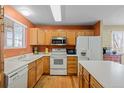 Functional kitchen with wood cabinets, white appliances, and an island at 10463 Adams St, Northglenn, CO 80233