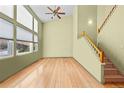 Bright living room with a vaulted ceiling, large windows, and hardwood floors leading to an adjacent staircase at 10463 Adams St, Northglenn, CO 80233