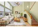 Bright living room with a vaulted ceiling, large windows, and hardwood floors leading to an adjacent staircase at 10463 Adams St, Northglenn, CO 80233