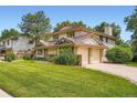 A well-maintained two-story home featuring a two-car garage, lush lawn, and mature trees on a sunny day at 4780 W 102Nd Pl, Westminster, CO 80031