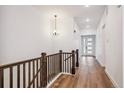 Bright hallway featuring wood floors, a chandelier, and neutral wall paint at 1111 Joseph Pl, Erie, CO 80026