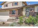 Close-up of the home's entrance with a decorative door, brick accents, and flower bed at 9270 Tennyson St, Westminster, CO 80031