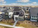 An aerial view of a two-story home with modern design, dark trim windows, and a well-manicured lawn at 6209 Stable View St, Castle Pines, CO 80108
