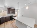 Modern kitchen featuring white quartz island, wood cabinets, stainless appliances, and wood floors at 1169 Highview Dr, Erie, CO 80516