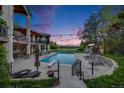 Spacious backyard with a large in-ground pool, lounge chairs, landscaped accents, and elegant two-story home at dusk at 10914 Remmick Ridge Rd, Parker, CO 80134