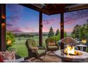 Comfortable screened-in porch with fire pit, cushioned chairs, and serene views of the surrounding landscape at dusk at 10914 Remmick Ridge Rd, Parker, CO 80134