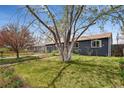 Front exterior featuring lush green lawn and mature trees creating shade at 3975 S Jason St, Englewood, CO 80110