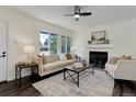 Bright living room with neutral walls, fireplace, ceiling fan, and large windows providing natural light at 3854 S Olathe Cir, Aurora, CO 80013