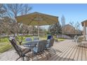A spacious backyard deck featuring outdoor seating with an umbrella and mature trees at 884 W 124Th Dr, Denver, CO 80234